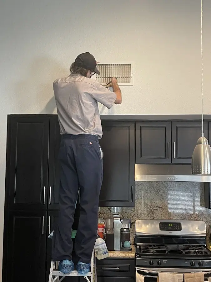 Technician inspecting an air vent during HVAC service in Eastmont